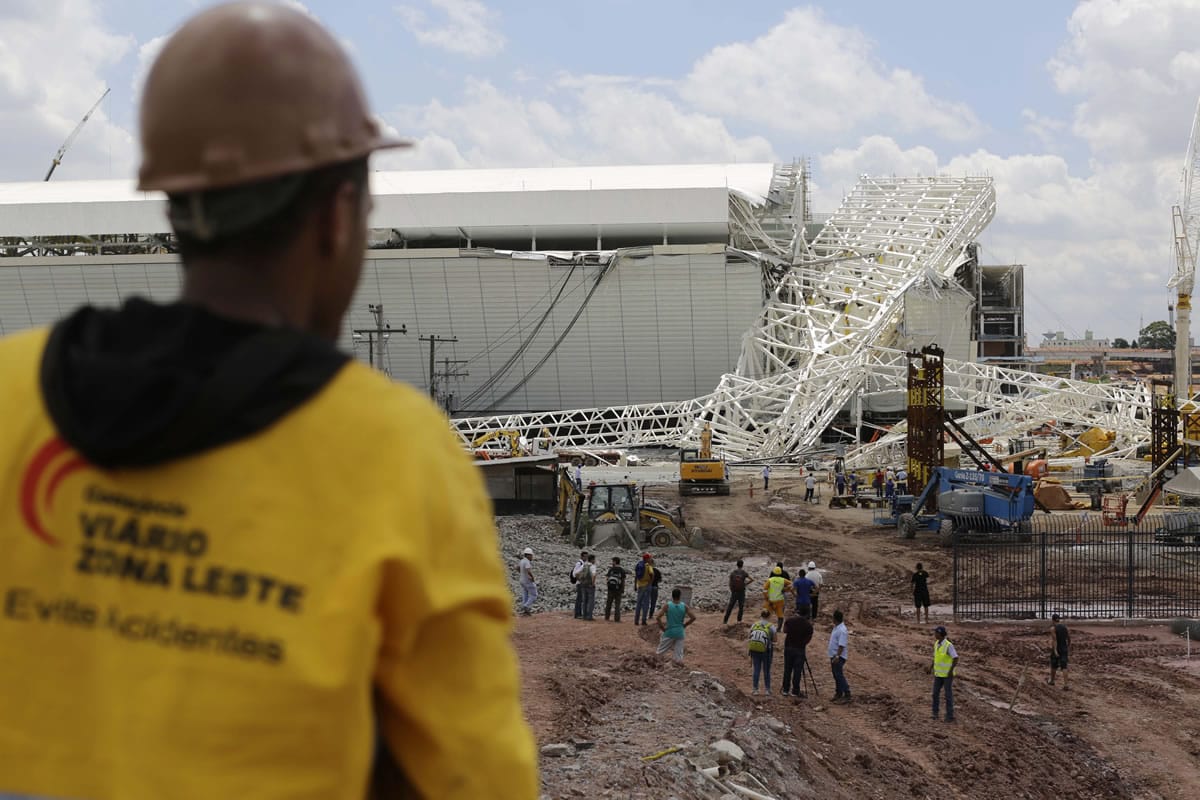 People stand Wednesday near a metal structure that buckled on part of the Itaquerao Stadium in Sao Paulo, Brazil.