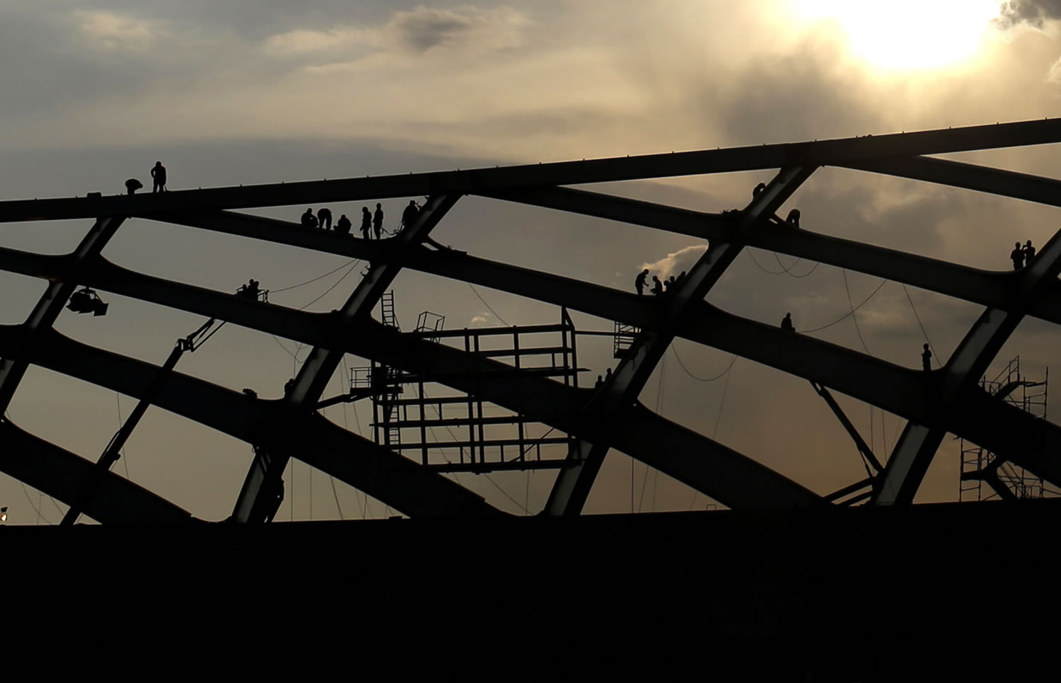 Construction workers works Tuesday on the roof of the Arena da Amazonia stadium, in Manaus, Brazil.