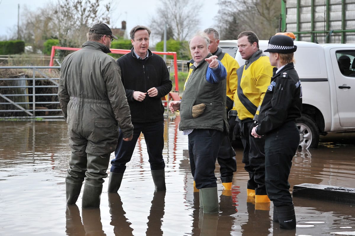 Prime Minister David Cameron, second left, visits Goodings Farm in Fordgate, southwest England, with Bridgwater and West Somerset MP Ian Liddell-Grainger, center, and farmer Tony Davy, left, Friday Feb. 7, 2014. Flood-hit villagers have lambasted Britain's Environment Agency chairman Chris Smith where thousands of acres have been underwater for more than a month. Bouts of rain, high tides and strong winds have pounded Britain since December, and this week washed away a stretch of the main rail line linking London and the southwest.
