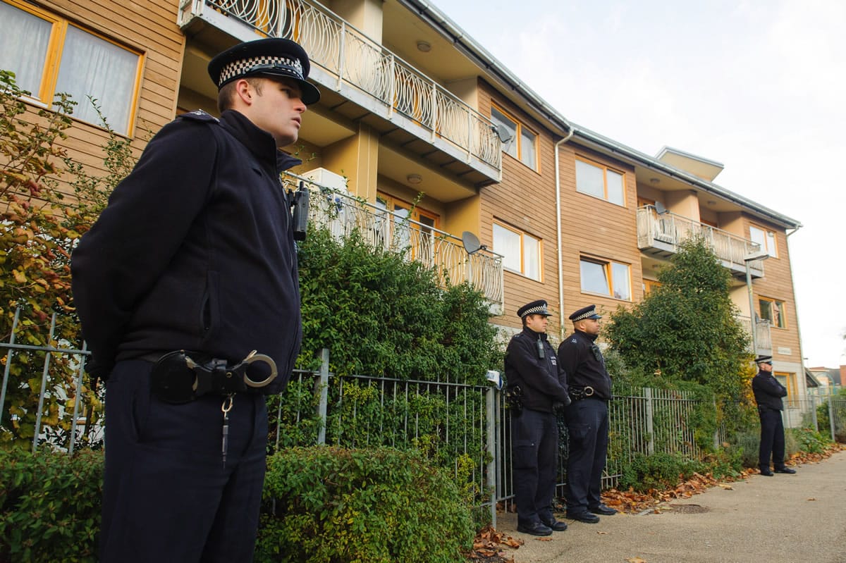 Officers stand outside apartments Saturday as police conduct house-to-house inquiries in the area where three women held as slaves were rescued in south London.