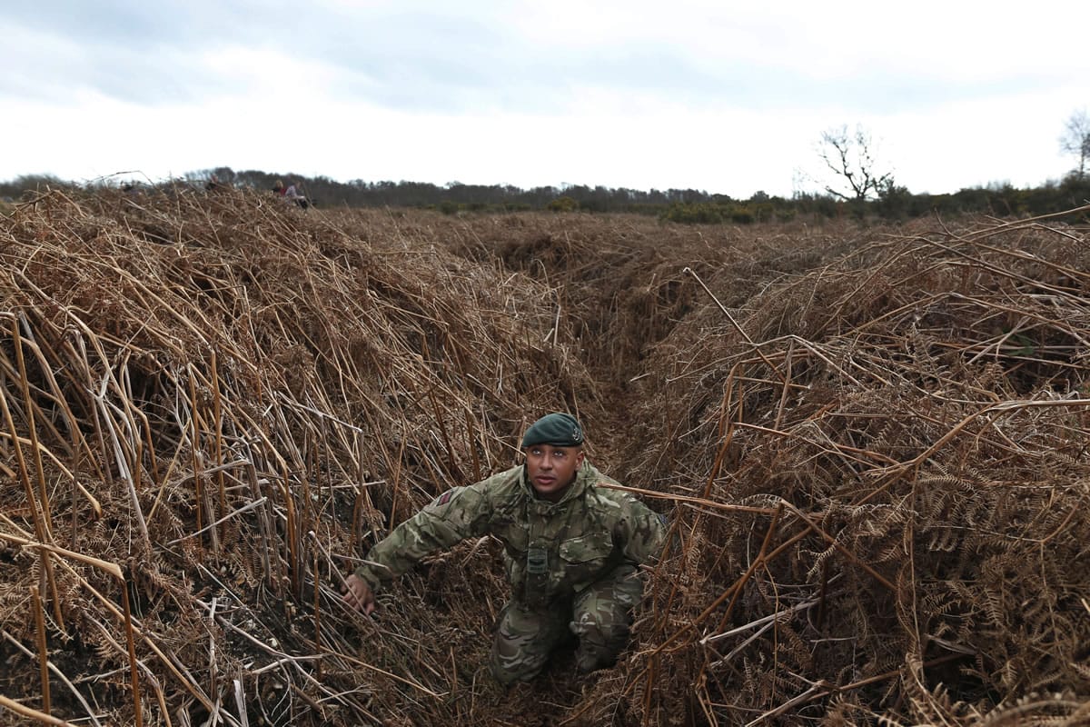 British army Lance Corporal Rob Walters kneels in a WWI practice trench Thursday in Gosport, southern England.