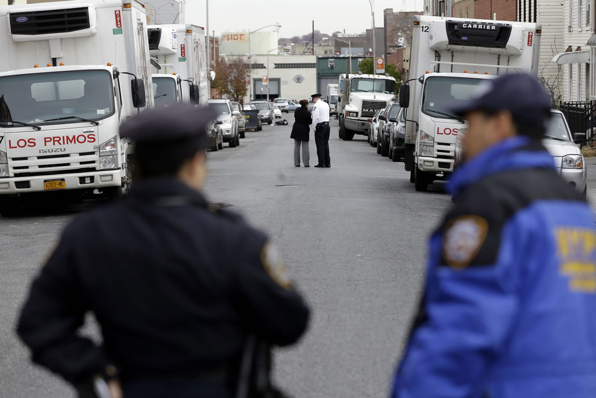 Police officers stand in the street near a crime scene in the Brooklyn section of New York on Monday.