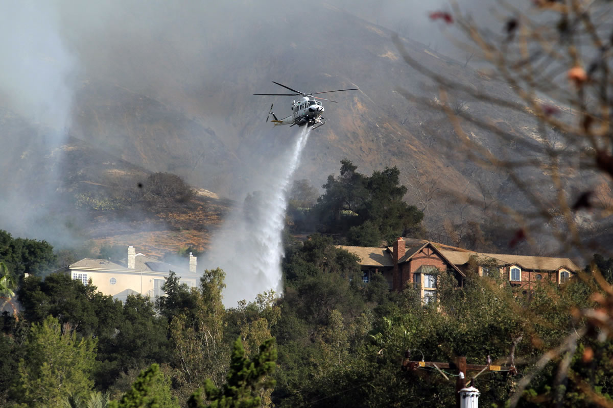 A firefighting helicopter makes a water drop over homes in Glendora, Calif., as a wildfire burns in the hills just north of the San Gabriel Valley community on Thursday.