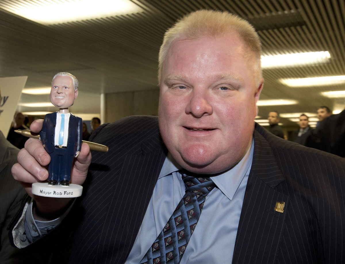 Toronto Mayor Rob Ford poses with a bobblehead doll in his likeness Tuesday at city hall in Toronto.