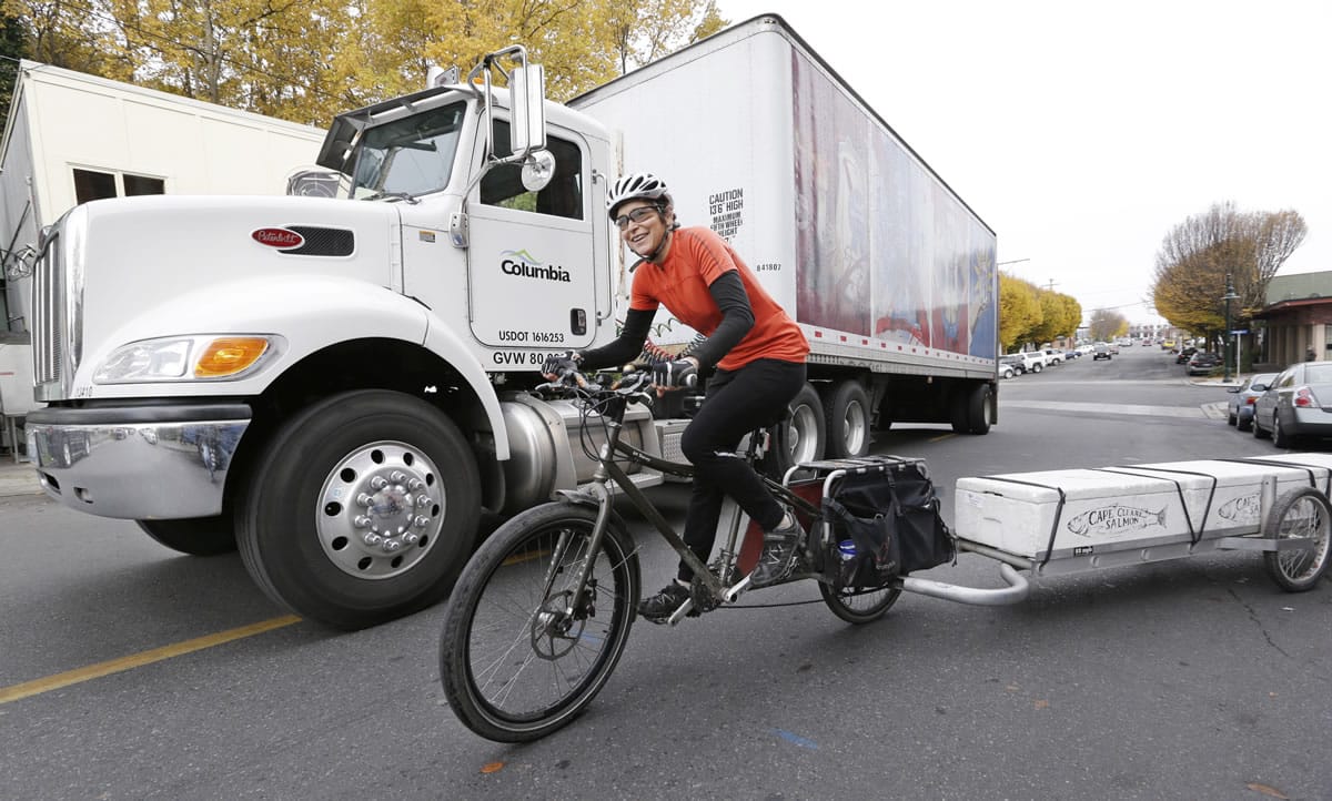 Heidi Lappetito pedals her cargo bike past a parked beer truck as she hauls a trailer loaded with frozen salmon in Port Townsend.
