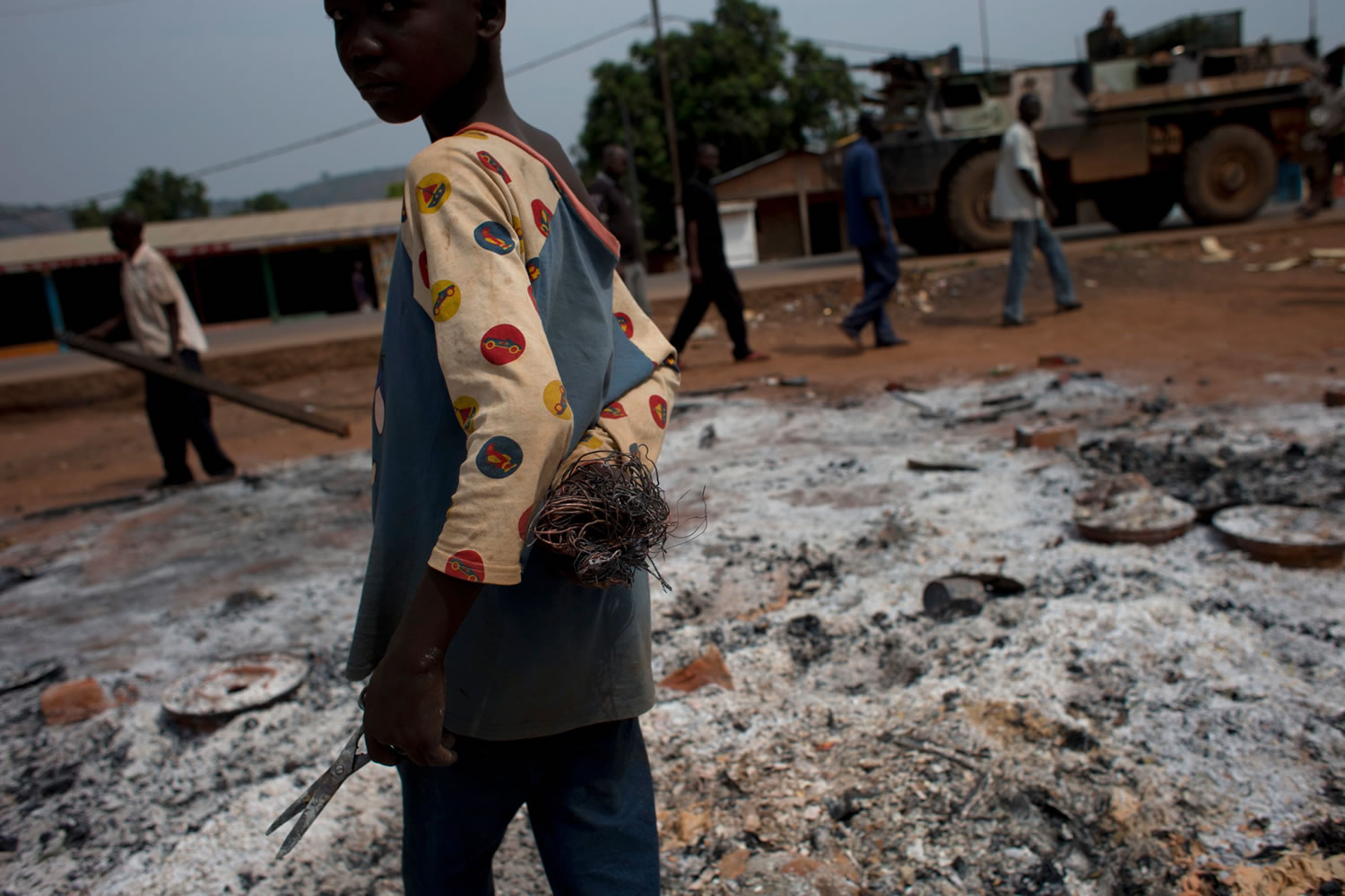 A boy salvages scraps of metal from the remains of burned shops, as French soldiers stand guard in a neighborhood where Chadian soldiers clashed with anti-balaka Christian militiamen on Wednesday afternoon, in the Gobongo neighborhood of Bangui, Central African Republic, on Thursday.