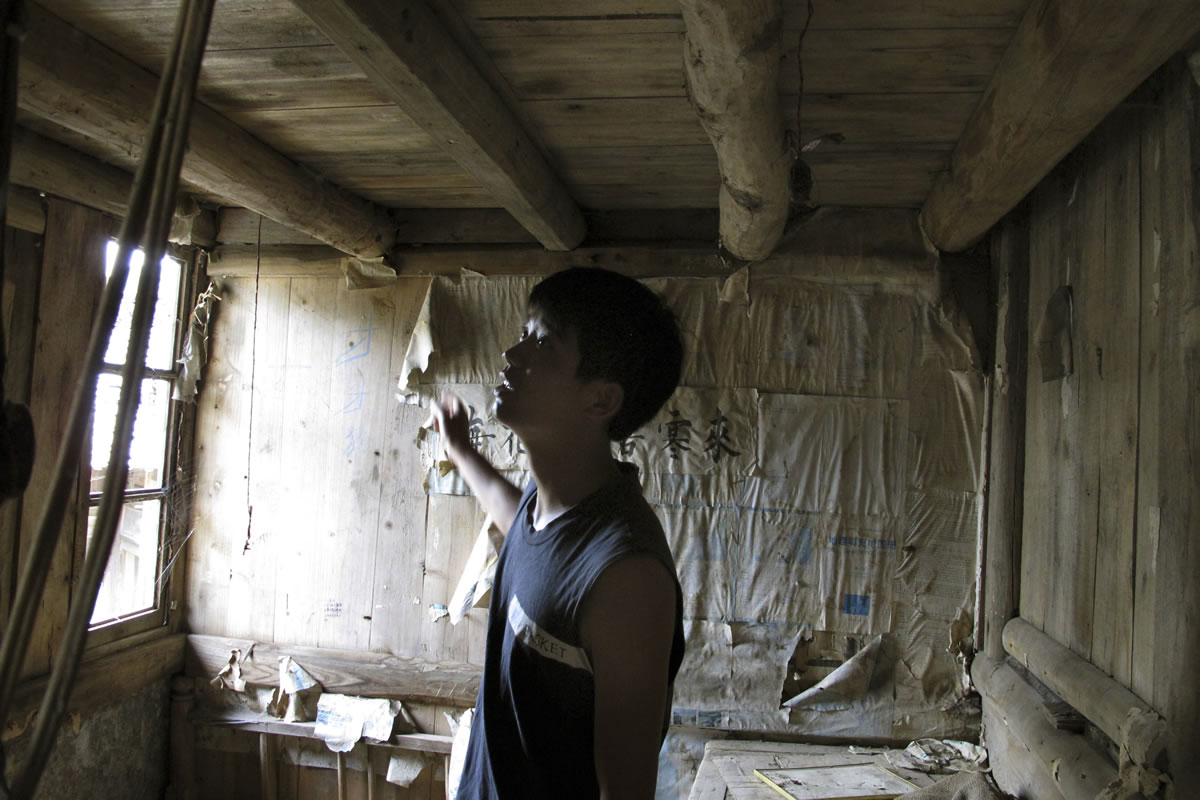 Mu Zhengwu surveys his room in his childhood home in China's Guizhou province, where he wrote inspiring words on the wall to keep himself from giving up on his studies.