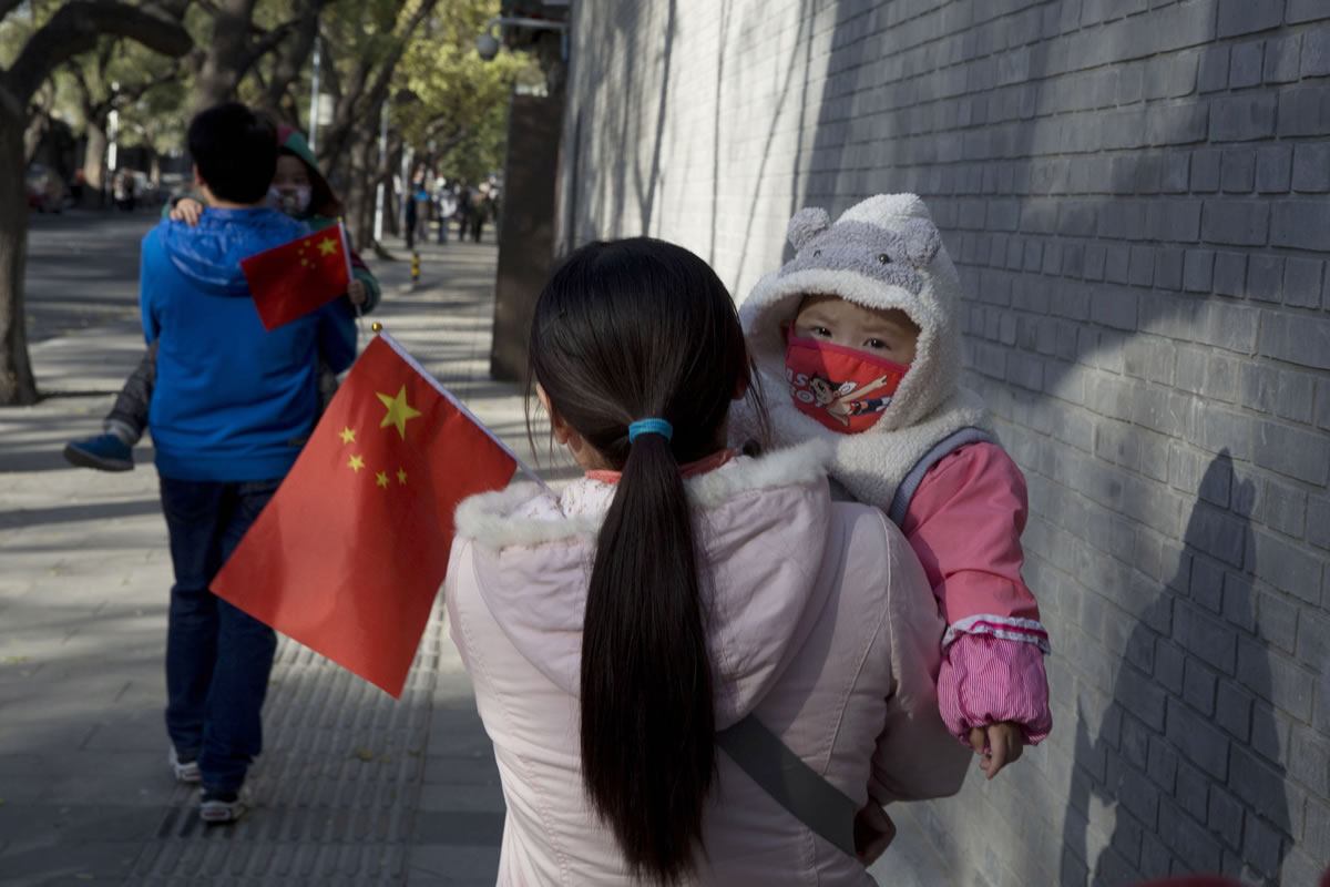 A visitor to the Forbidden City in Beijing carries a child holding the Chinese flag on Saturday.