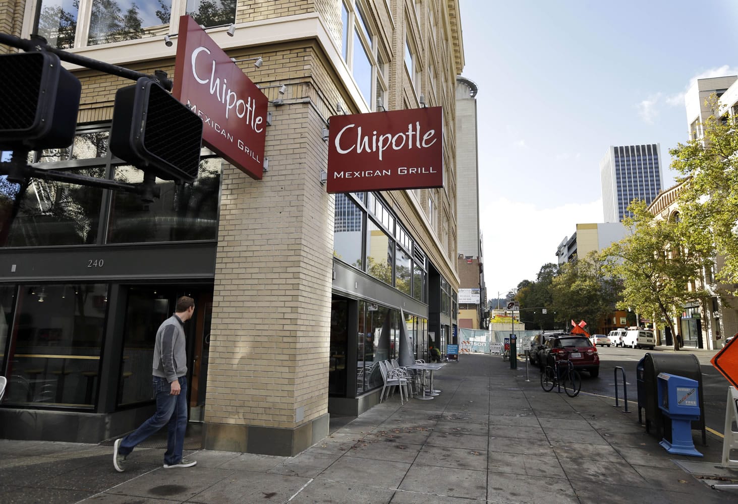 A pedestrian walks past a closed Chipotle restaurant in Portland on Monday. Chipotle voluntarily closed down 43 of its locations in Washington and in the Portland area as a precaution after an E. coli outbreak linked to six of its restaurants in the two states has sickened nearly two dozen people.