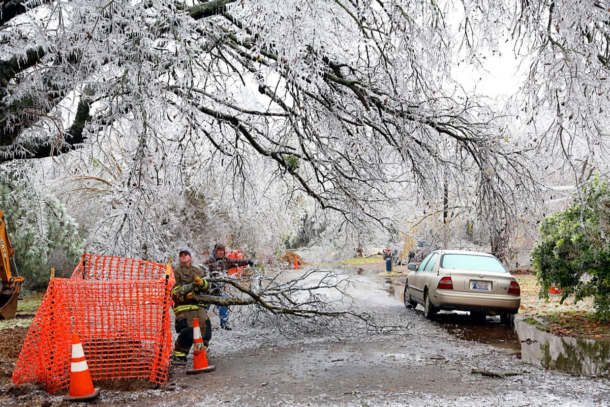 A firefighter and a homeowner work together to clear a street of debris from an ice storm Friday in Paris, Texas.