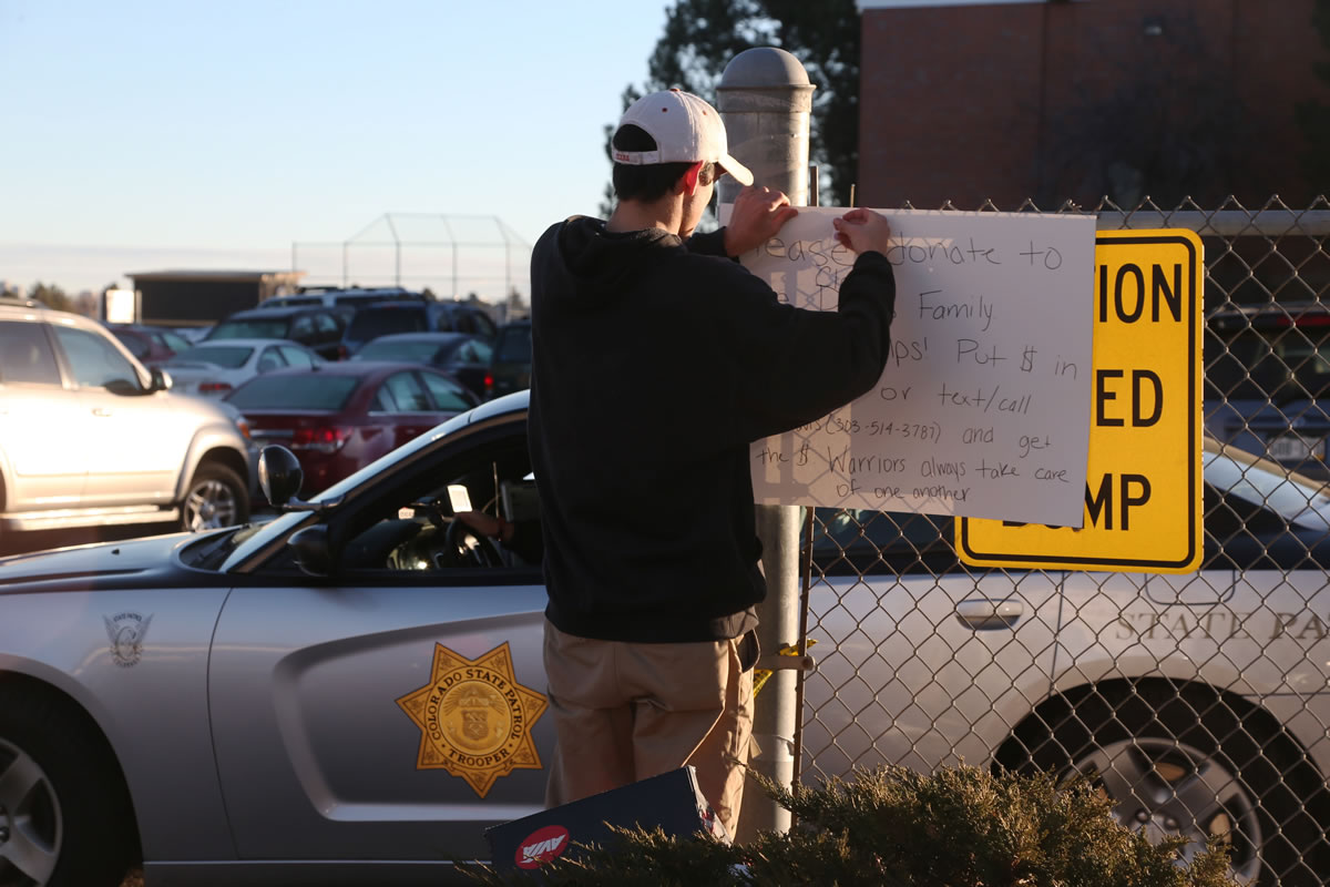 Chris Davis, a senior who plays basketball at Arapahoe High School, hangs a sign Saturday to raise money for the victim in a shooting at the school in Centennial, Colo. Investigators were working to find out what motivated a teenage gunman to enter his suburban Denver high school armed with a shotgun looking for a specific teacher a day earlier.