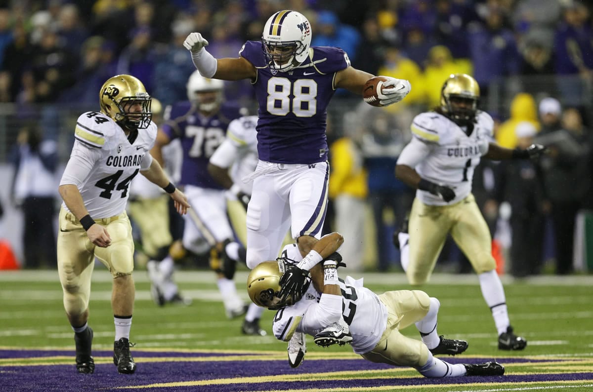 Washington tight end Austin Seferian-Jenkins (88) is tackled by the leg by Colorado defensive back Greg Henderson, bottom, as Colorado's Addison Gillam (44) looks on in the first half of an NCAA college football game on Saturday, Nov. 9, 2013, in Seattle. (AP Photo/Ted S.