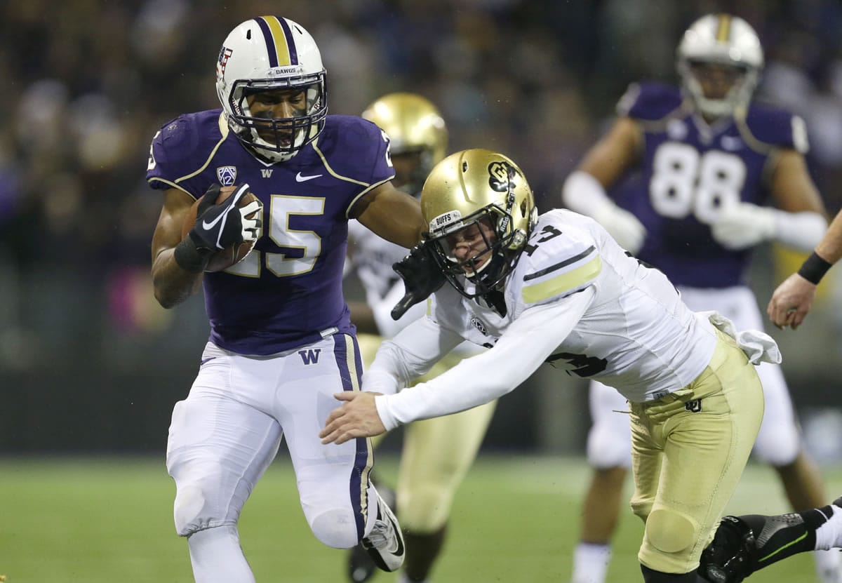 Washington running back Bishop Sankey pushes Colorado defensive back Parker Orms, right, out of the way in the first half Saturday in Seattle.