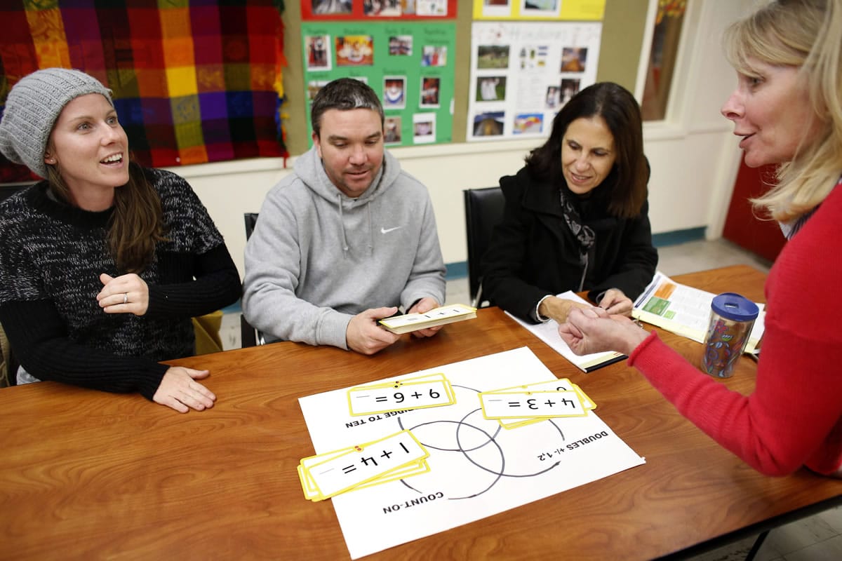 Parents Kate Ezyk, left, and her husband, Matt Ezyk, both of Westerly, Mass., practice Common Core math techniques with elementary school principal Polly Gillie, far right, during a math workshop at a community center in Westerly as math specialist Gina Gervasini looks on.