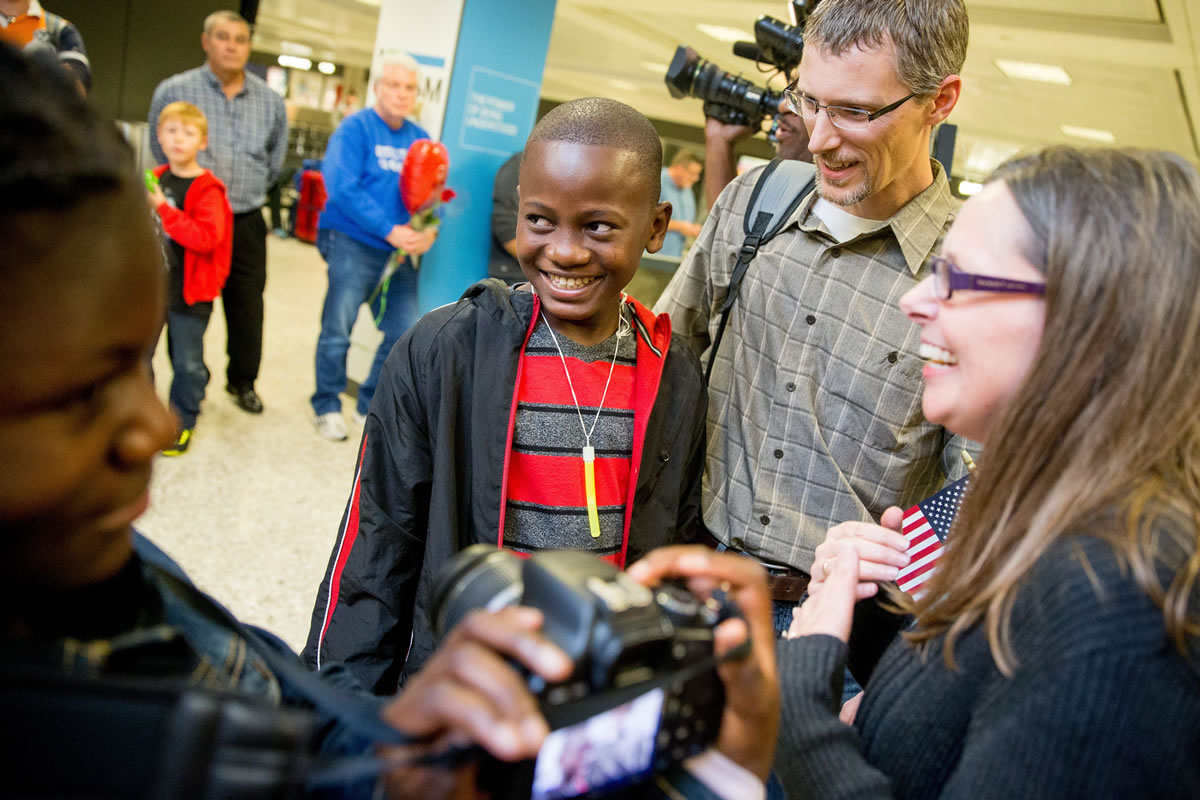 Jennifer and Eric Sands of Illinois, right, accompanied by their adopted daughter, Joy, 12, left, smile as their adopted son, Issaac, 12, center arrives Wednesday from Congo at Dulles International Airport in Dulles, Va.