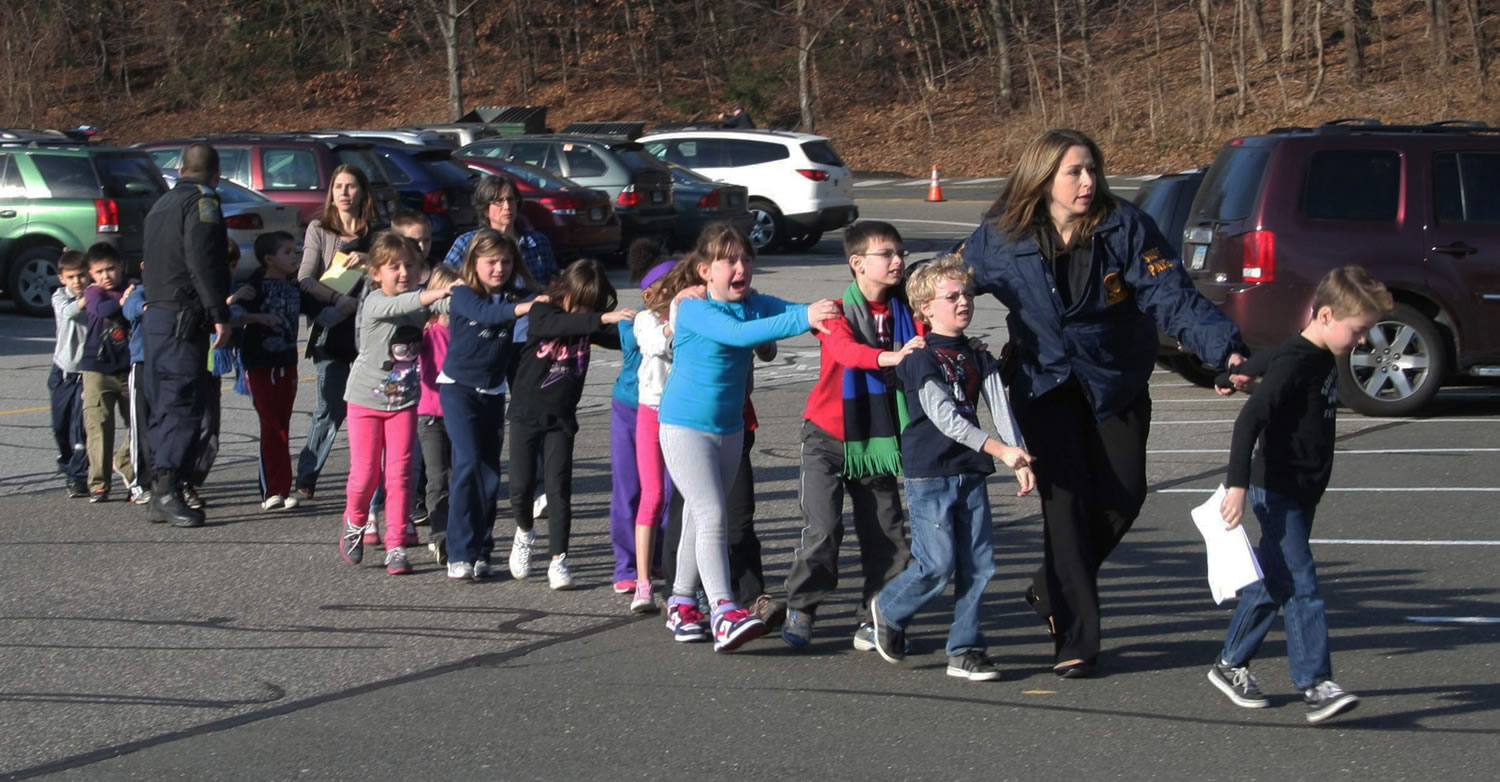 Connecticut State Police lead a line of children from the Sandy Hook Elementary School in Newtown, Conn. on Friday, Dec.