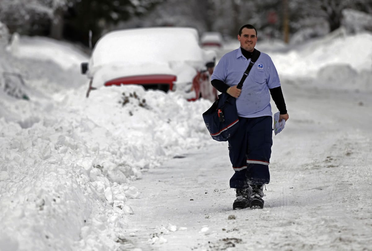 Postal carrier Derek Thurston makes his way down a snow-covered street Wednesday as he delivers mail in Indianapolis.
