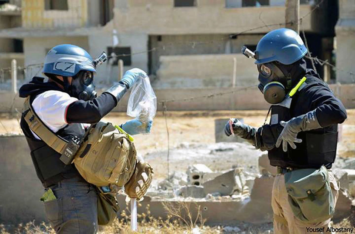 Members of the United Nations investigation team take samples from sand near a part of a missile that is likely to be a chemical rocket, according to activists, in the Damascus countryside of Ain Terma, Syria.