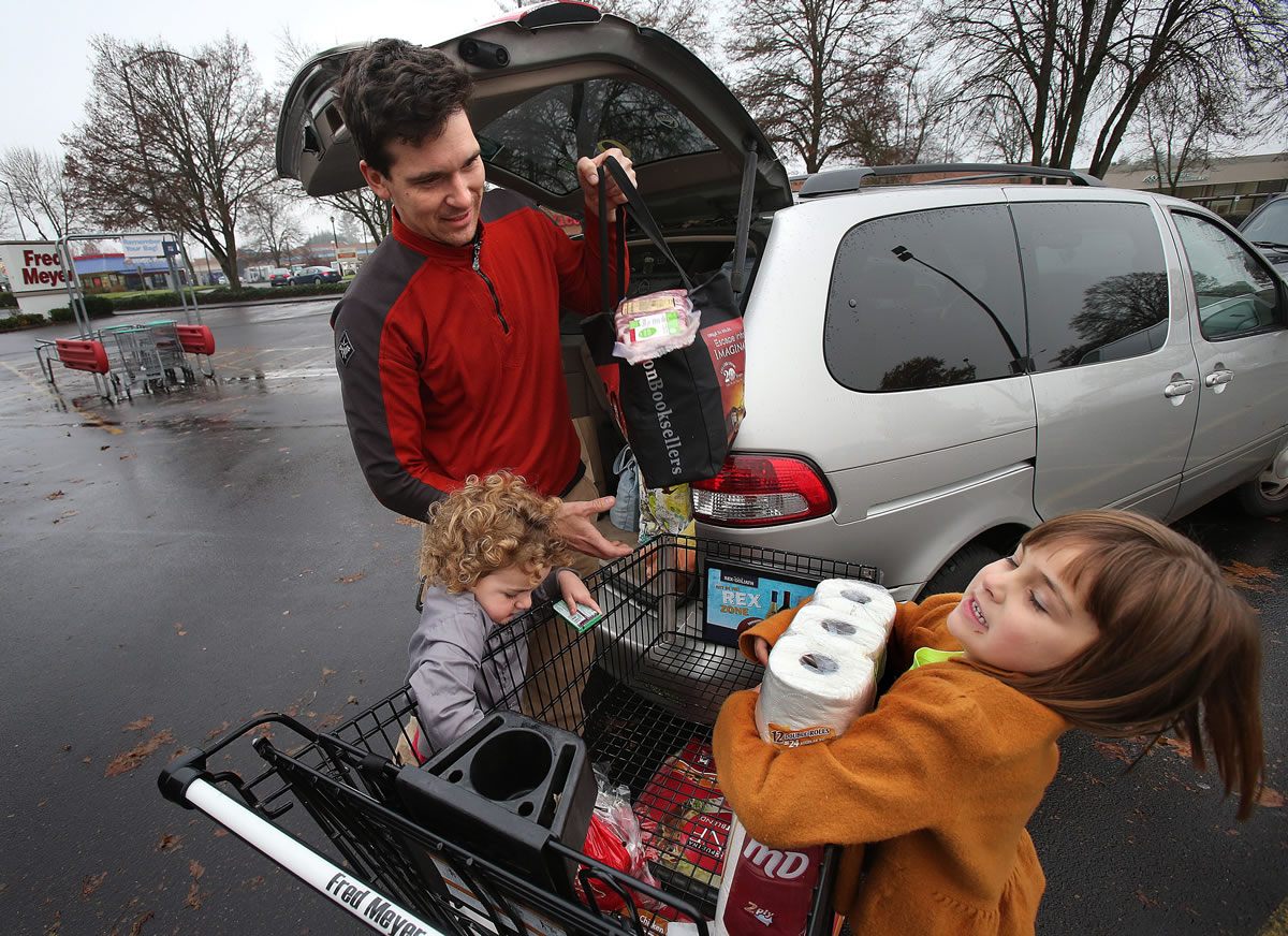 Tracy Brandt of Eugene uses reusable canvas bags and the help of his two children, Violet Brandt, 6, and Leo Brandt, 3, to load the family groceries into their vehicle Nov.