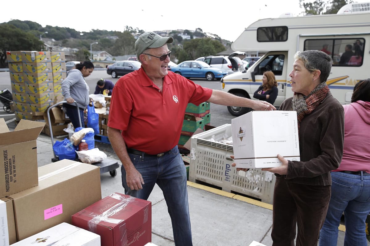 Steve Bosshard, center, smiles after giving out a specially prepared box of food at a food bank distribution in Petaluma, Calif.