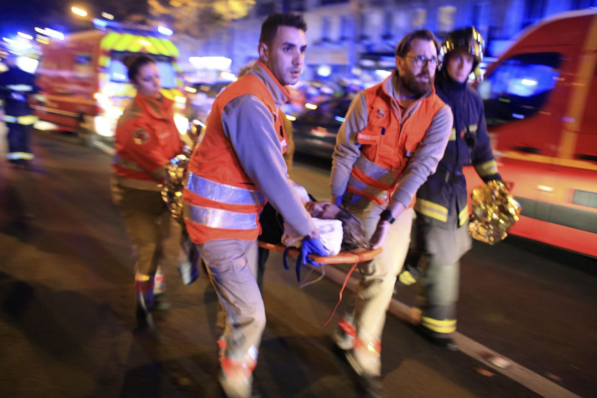 FILE - In this Nov.13, 2015 file photo, a woman is being evacuated from the Bataclan concert hall after a shooting in Paris. Simply by staying alive, the hundreds of injured in the Paris attacks are defying the Islamic State terrorists who sought to kill them. Some were in cardiac arrest when evacuated to hospitals but now look like they will pull through. For others with smashed spines and other handicapping wounds, the months and years ahead could be a daily battle.