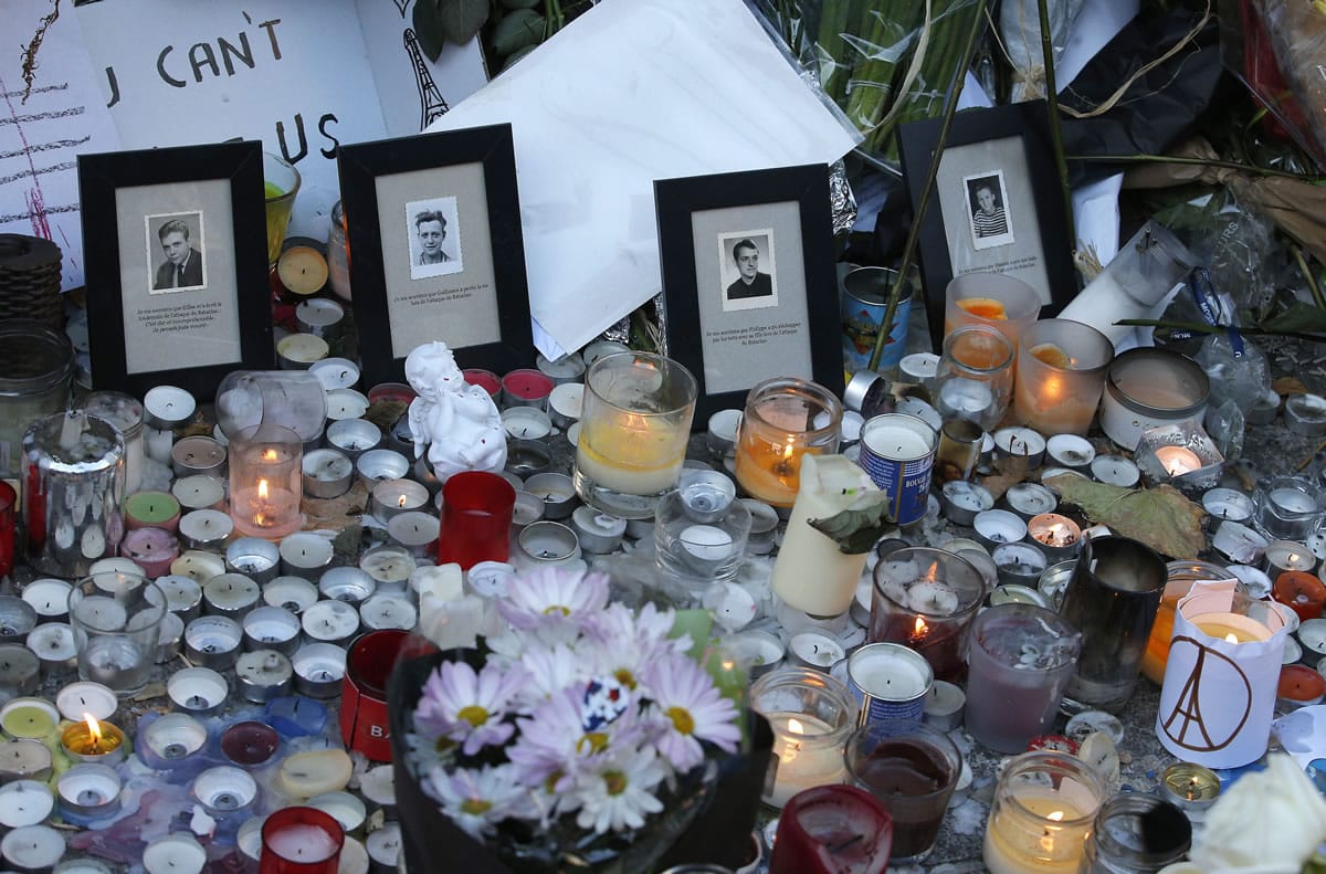 Pictures of victims are placed behind candles Sunday outside the Bataclan concert hall in Paris. Thousands of French troops deployed around Paris on Sunday and tourist sites stood shuttered in one of the most visited cities on Earth while investigators questioned the relatives of a suspected suicide bomber involved in the country&#039;s deadliest violence since World War II.