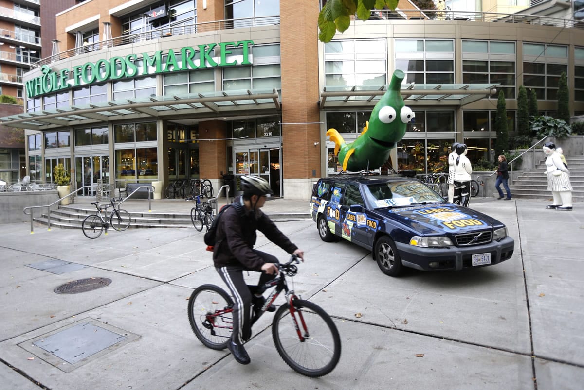 A cyclist rides past a car with a figure of a soybean crossed with a fish on top of of it Tuesday.