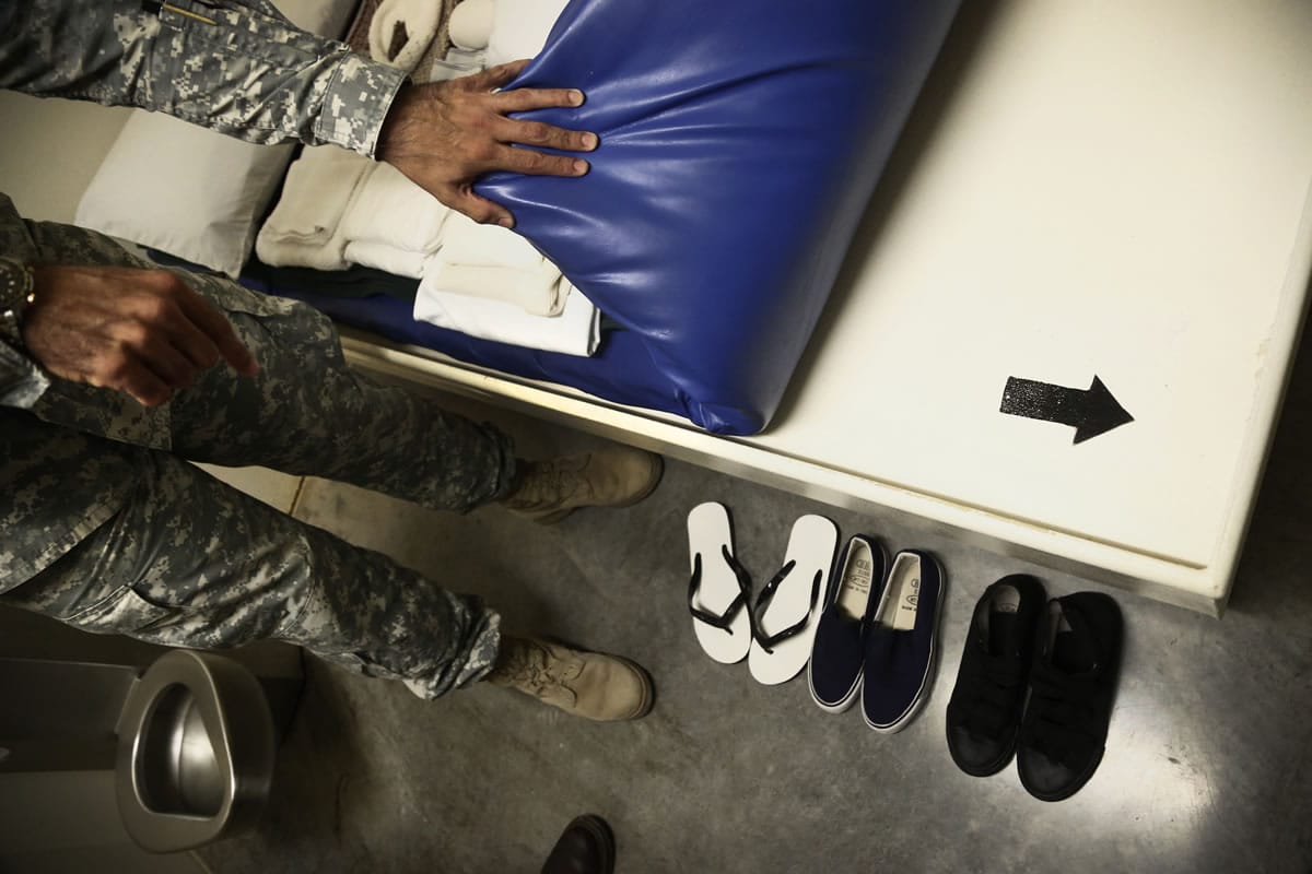 A U.S. Army guard pulls back a mattress showing a painted arrow pointing towards Mecca, for Islamic prayer, during a tour of Camp VI detention facility for captured al-Qaida and Taliban militants at Guantanamo Bay Naval Base, Cuba, on Nov.