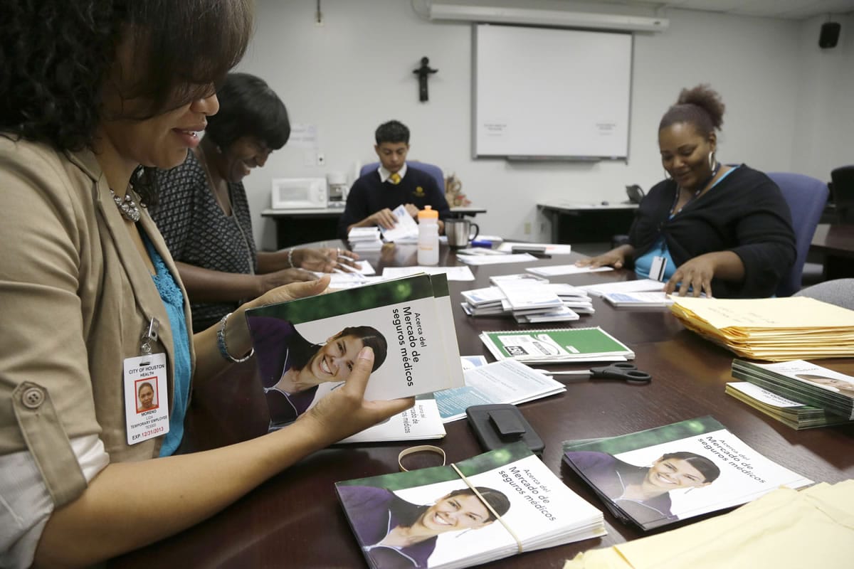 Temporary city Of Houston employee Lida Moreno, left, and colleagues count out Spanish language brochures for Enroll America in preparation of a door-to-door distribution in Houston.