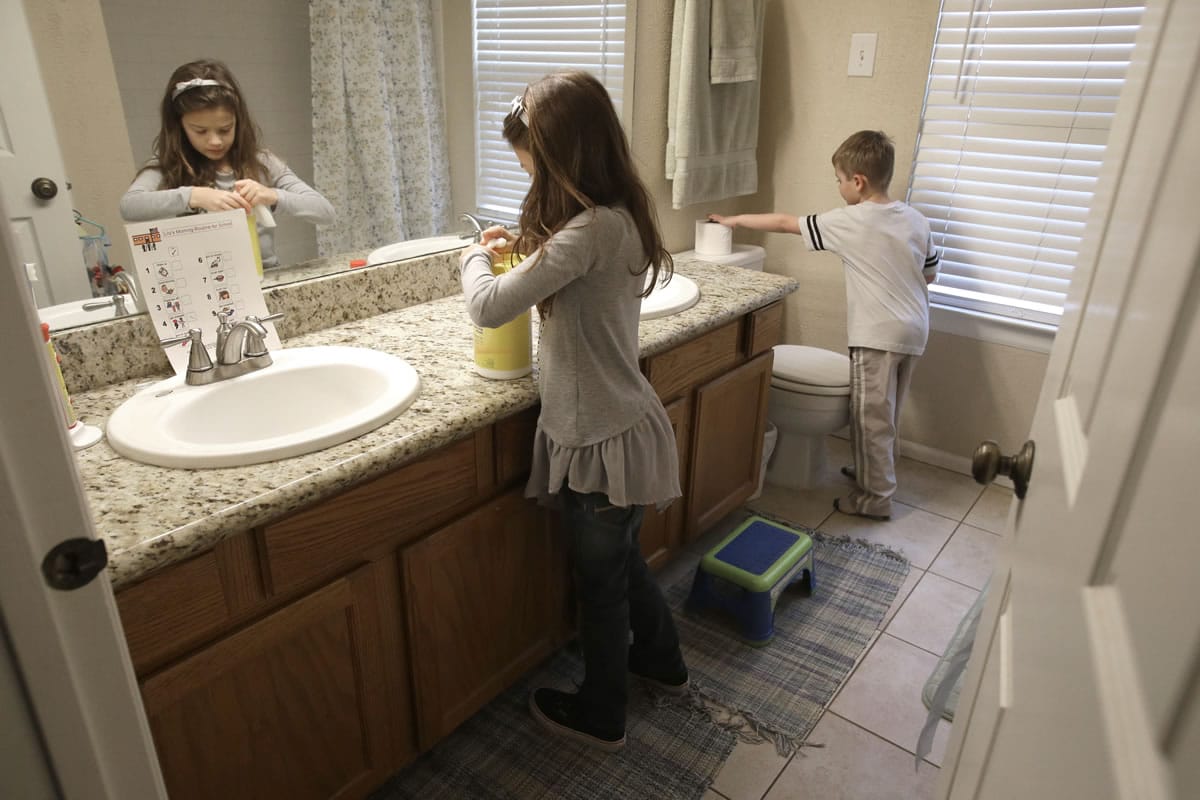 Lily Cherry, 8, cleans her bathroom as her brother, Aiden, 6, right, puts out a new roll of toilet paper at their home in Kingwood, Texas. Their mother, Andrea Cherry, has passed on her childhood practice of doing chores to her children believing it gives them a sense of family responsibility.