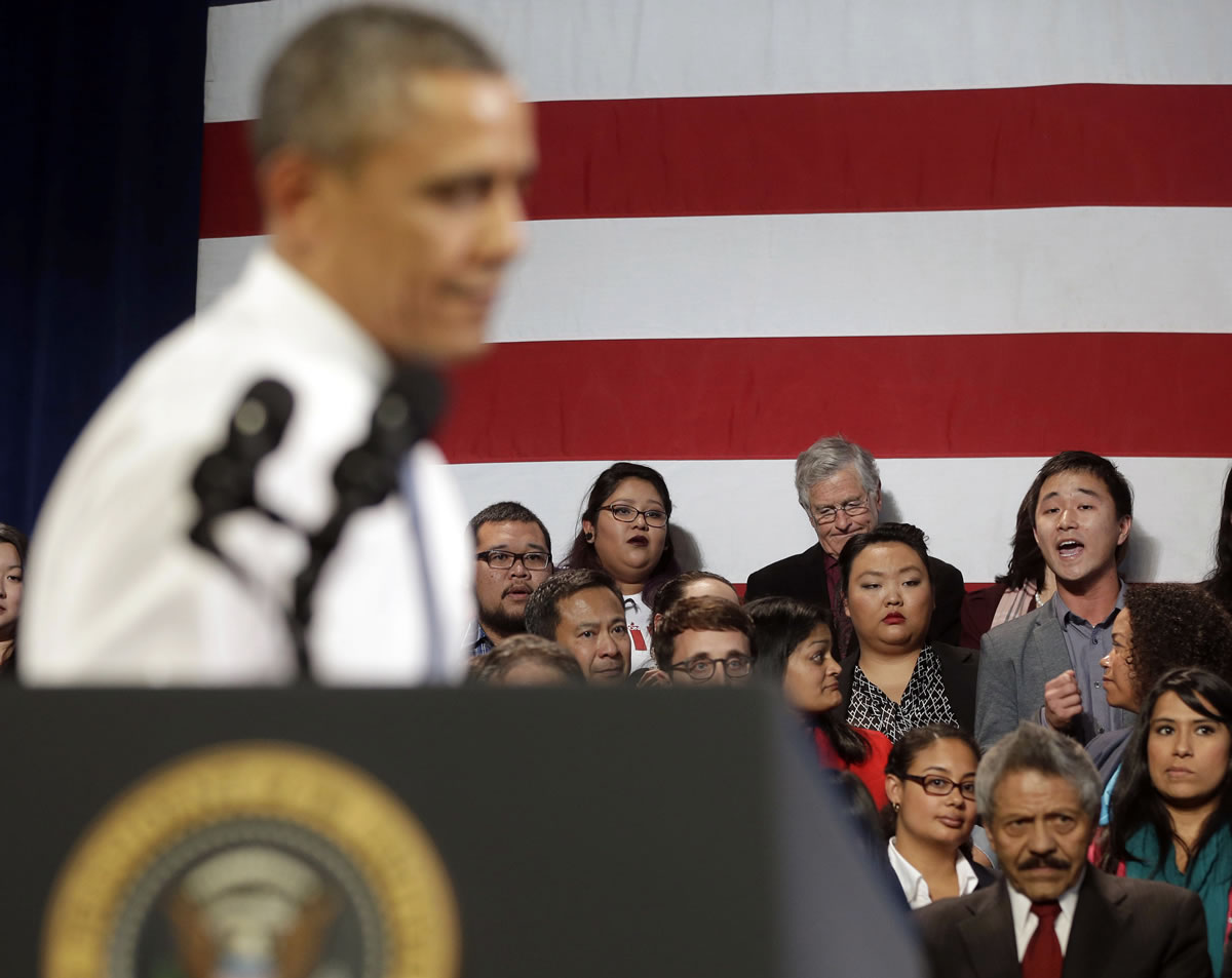 President Barack Obama, left, stops his speech and turns around in response to an unidentified man who heckled him about anti-deportation policies, at the Betty Ann Ong Chinese Recreation Center in San Francisco.