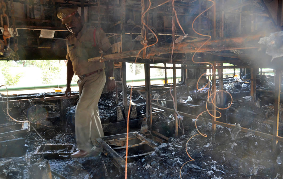 A policeman inspects the damage inside a train Saturday after a fire at Kothacheruvu, about 96 miles north of Bangalore, India.