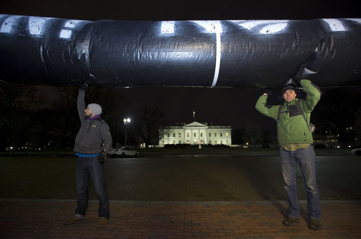 Activists hold up a pipeline made of black plastic during a protest Feb. 3 in Lafayette Park across from the White House.