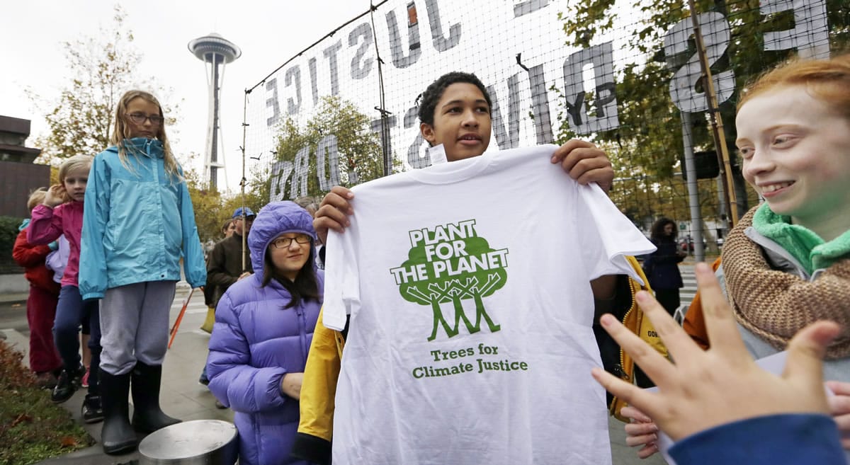 Environmental activist Aji Piper, 15 and a Seattle high school sophomore, holds up a T-shirt he was symbolically presenting to Bill Gates on Wednesday as he stands with other youth after a rally in Seattle.