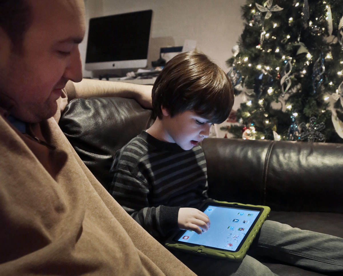 Adam Cohen watches as his son, Marc, 5, uses a tablet Dec. 3 at their home in New York.