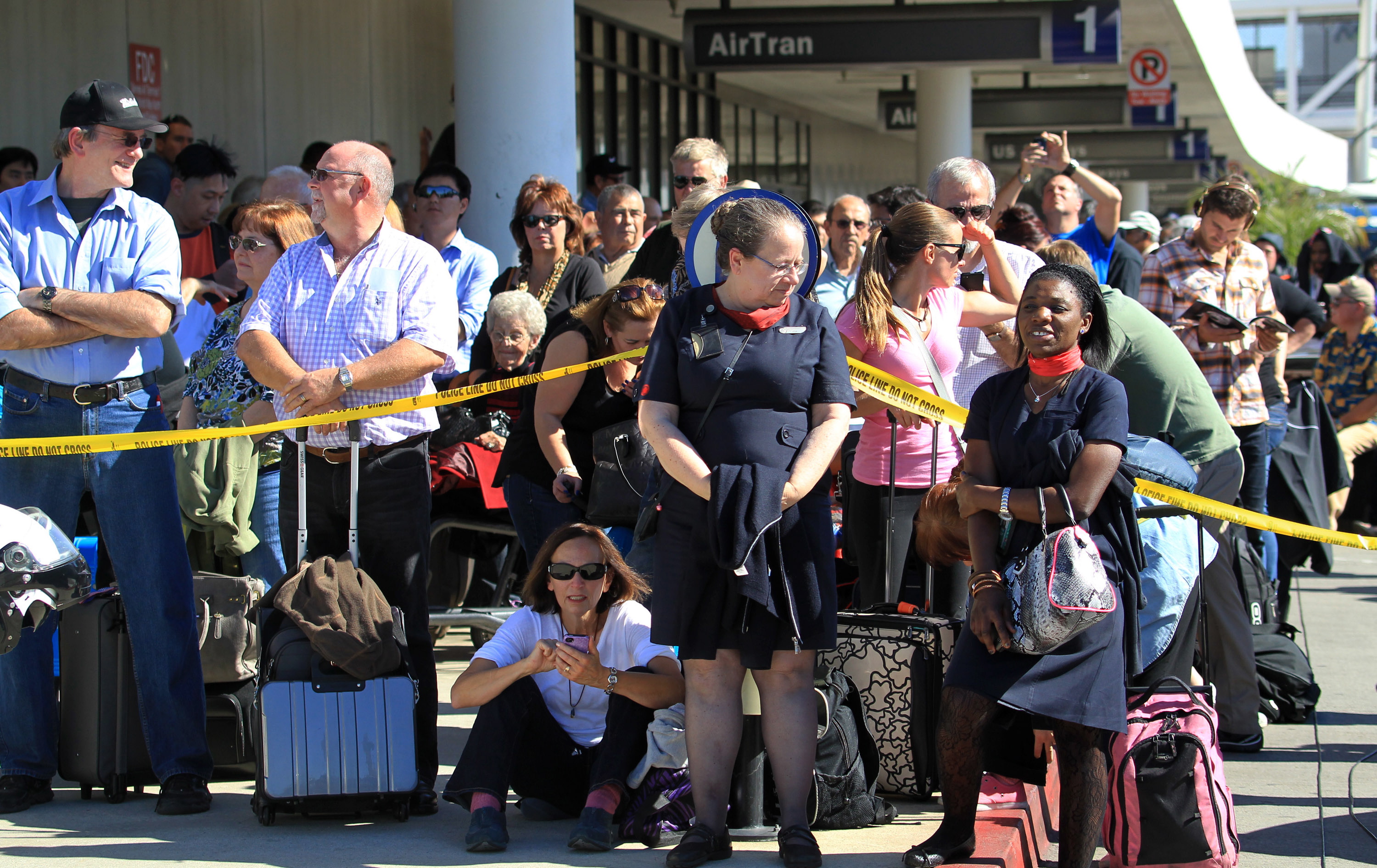 Passengers evacuated from a Los Angeles International Airport terminal where a shooting occurred Friday wait outside.