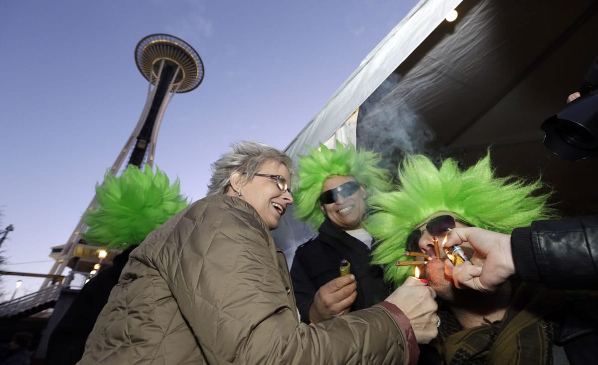 Jeremy Cooper, right, is helped by friends Cecilia Sivertson, left, and David DesRoaches in lighting three joints at once at a pot party Friday at the Seattle Center.