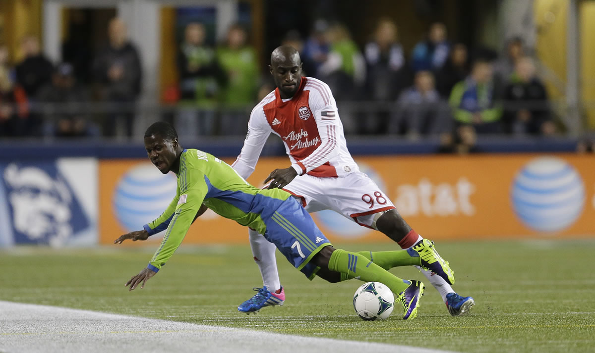 Seattle Sounders' Eddie Johnson, left, goes down as he battles with Portland Timbers' Mamadou Danso (98) for the ball in the first half of the first game of the Western Conference semifinals in the MLS Cup soccer playoffs, Saturday, Nov. 2, 2013, in Seattle. (AP Photo/Ted S.