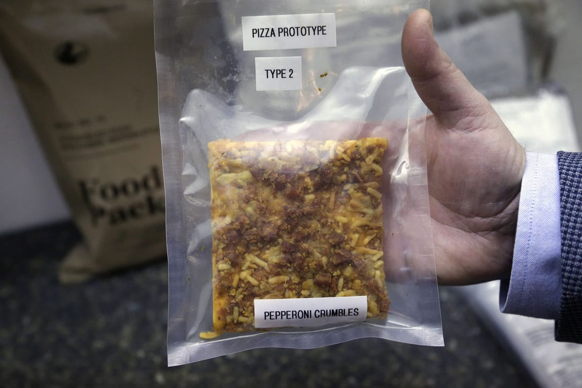 A packet containing a slice of prototype pizza is displayed by public affairs officer David Accetta at the U.S. Army Natick Soldier Research, Development and Engineering Center, in Natick, Mass. Pizza is in development to be used in individual field rations known as meal ready to eat, or MREs.