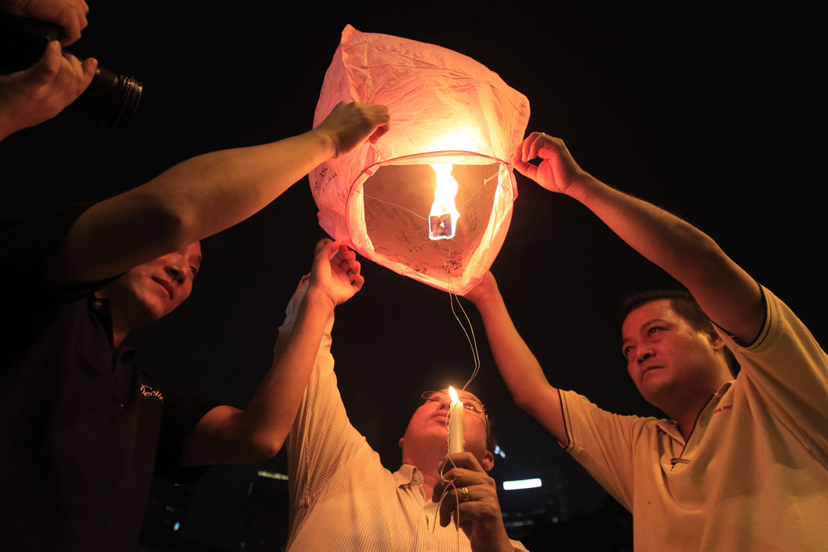 People prepare to release a sky lantern during a candlelight vigil for passengers aboard a missing Malaysia Airlines plane in Kuala Lumpur, Malaysia, on Monday.