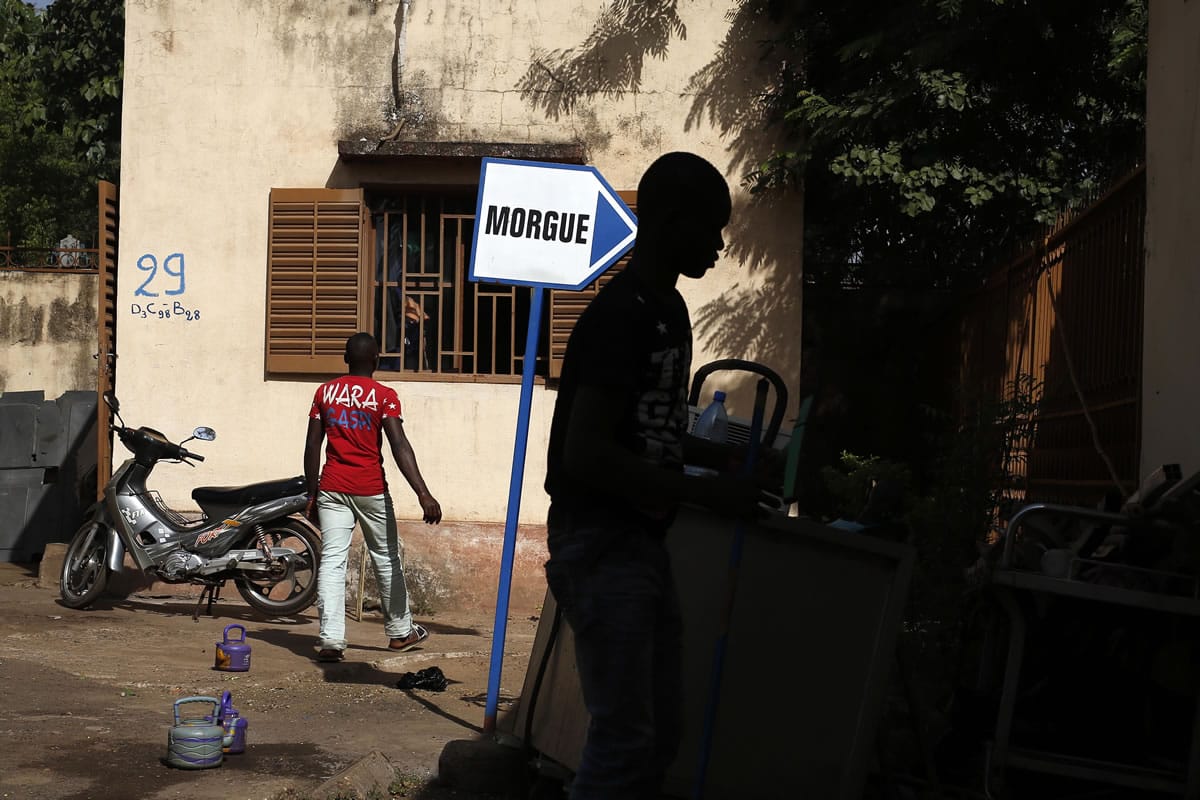 Hospital workers walk outside the morgue of the Gabriel Toure hospital in Bamako, Mali, Sunday. The heavily armed Islamic extremists who shot up a luxury hotel in Mali&#039;s capital, killing 19 people, timed their assault for the moment when guards would be the most lax, allowing them to easily blast their way past a five-man security team before turning their weapons on terrified guests, a security guard and witnesses said Saturday.