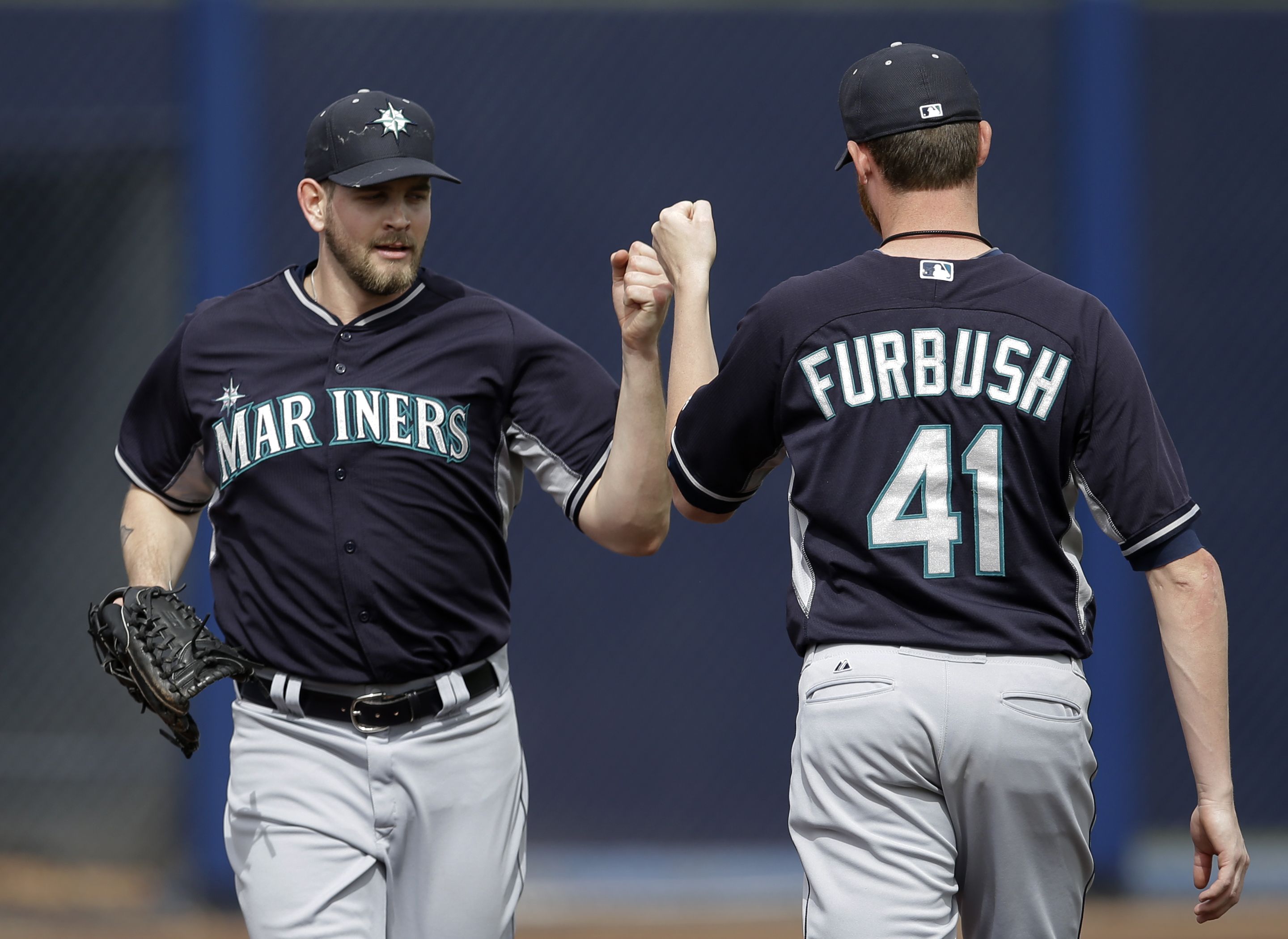 Seattle Mariners' James Paxton, left, and Charlie Furbush (41) fist-bump as they pass each other going and coming from the dugout to the bullpen in the fourth inning of an exhibition baseball against the San Diego Padres on Friday.