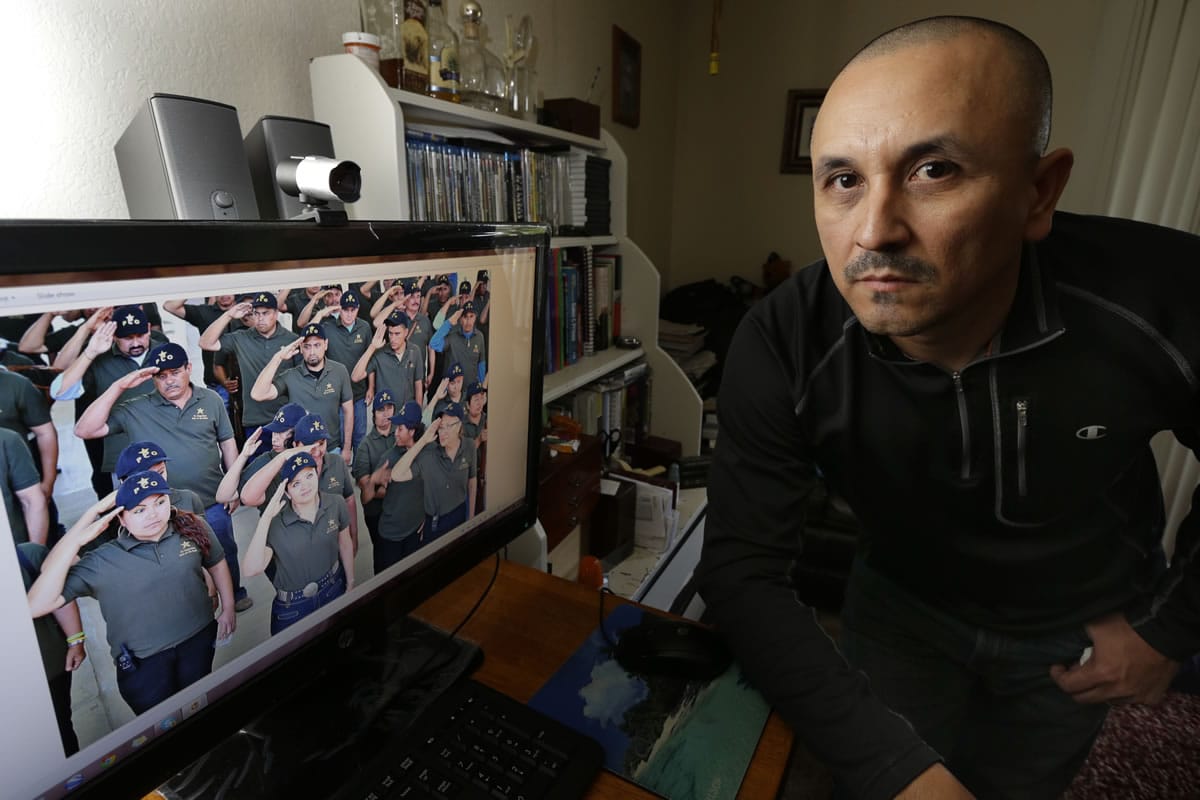 Jose Avila poses for a photo Tuesday in his apartment in Renton next to a computer monitor that shows a photograph of his wife, Nestora Salgado, second from front left.