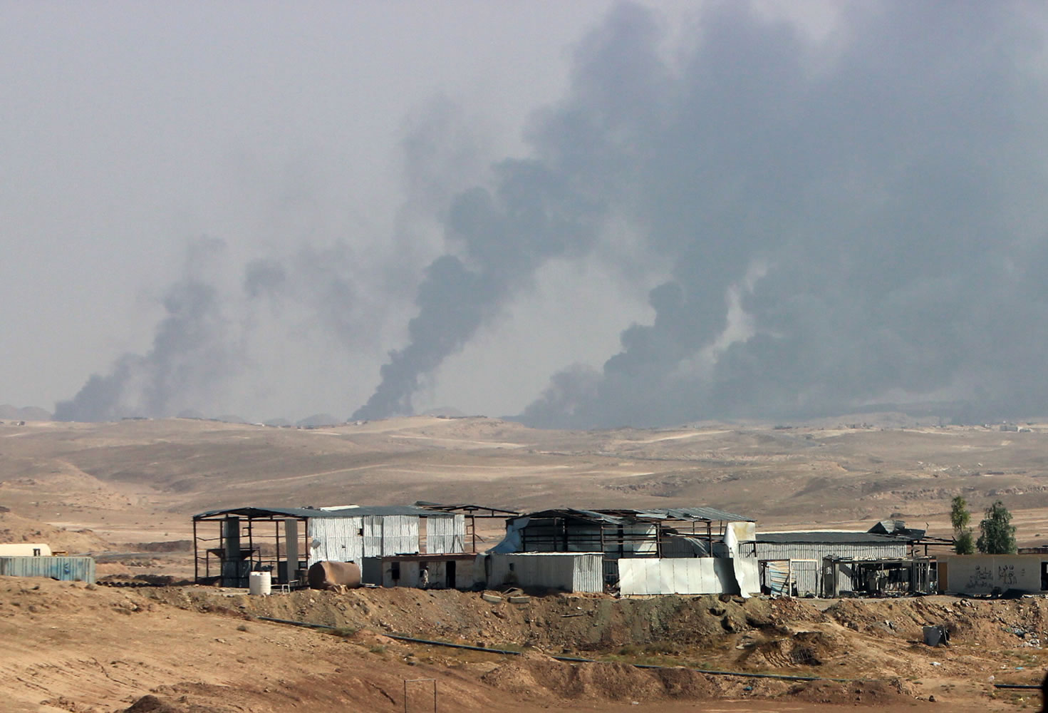 FILE - In this Saturday, Oct. 24, 2015, file photo, smoke rises as Iraqi security forces and allied Popular Mobilization Forces shell Islamic State group positions at an oil field outside Beiji, some 250 kilometers (155 miles) north of Baghdad, Iraq. The United States and Russia are going after the Islamic State group?s oil industry, destroying refineries and hundreds of tanker trucks transporting oil from eastern Syria in a heavy bombardment in recent days aiming to break the extremists? biggest source of income.