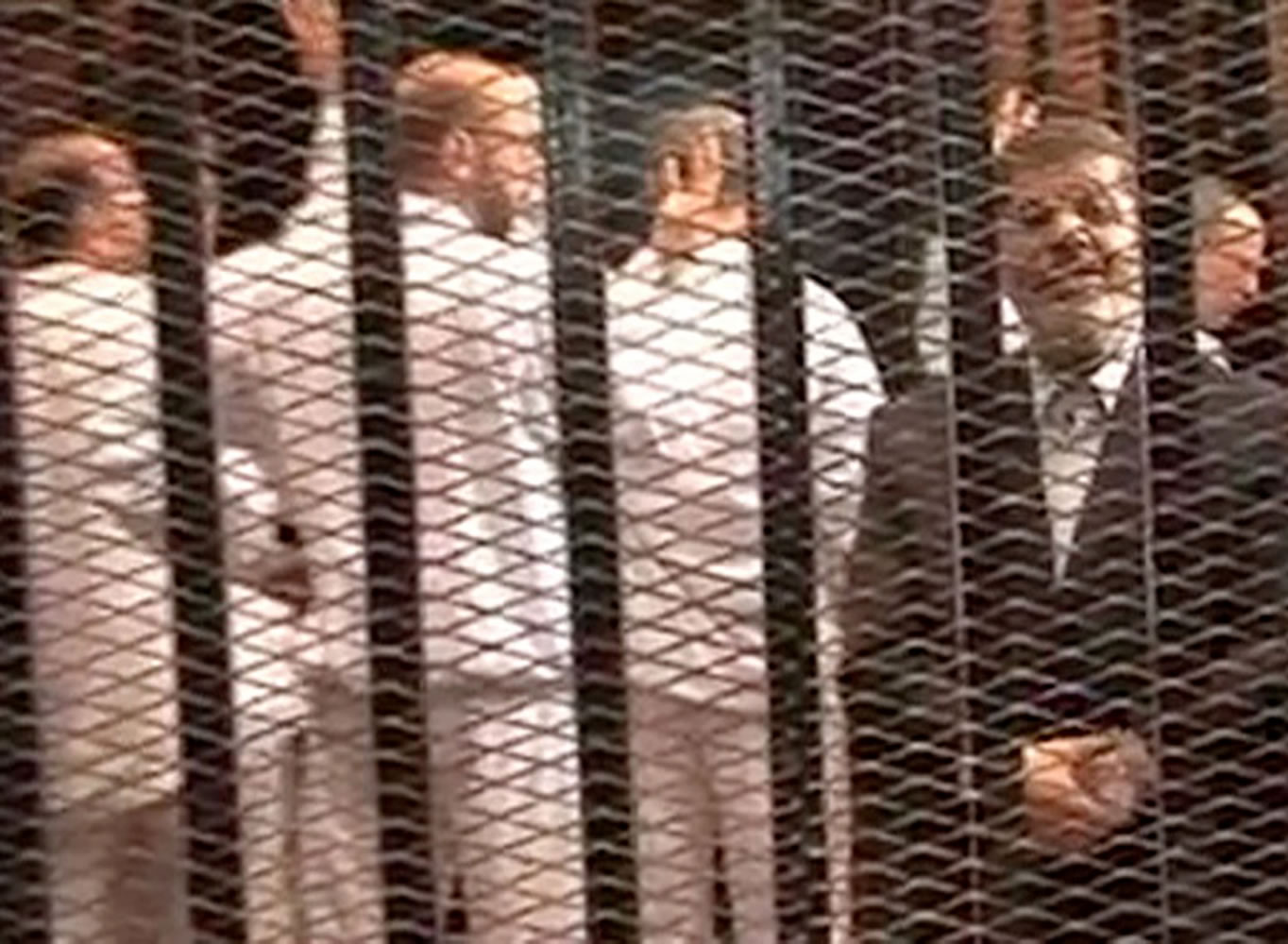 Ousted President Mohammed Morsi, right, speaking from the defendant's cage as he stands with co-defendants in a makeshift courtroom during a trial hearing in Cairo, Egypt in May.