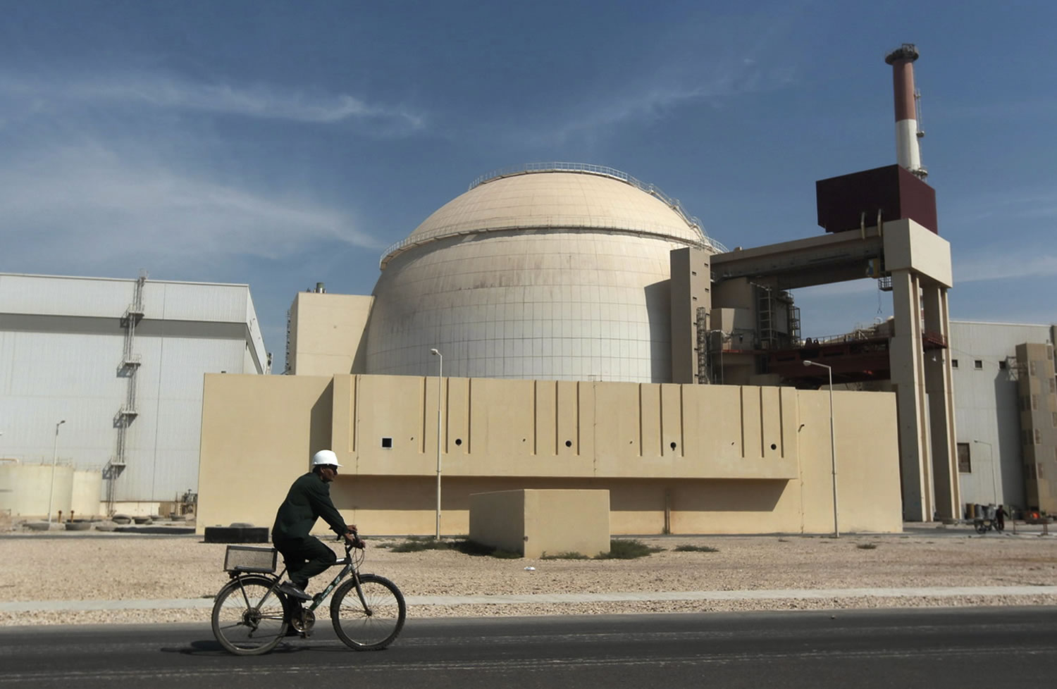 A worker rides a bicycle in front of the reactor building of the Bushehr nuclear power plant, just outside the southern city of Bushehr, Iran, in October 2010. Iran and six world powers have agreed on how to implement a nuclear deal struck in November, with its terms starting from Jan.