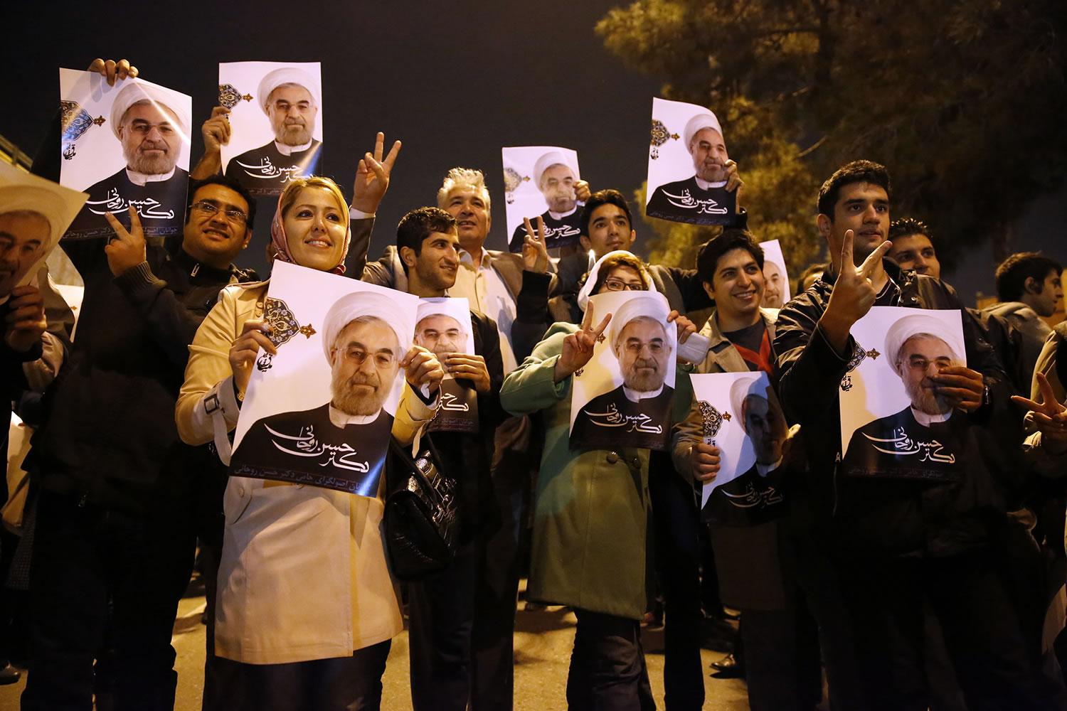 Iranians hold posters of President Hassan Rouhani as they welcome Iranian nuclear negotiators upon their arrival from Geneva at the Mehrabad airport in Tehran, Iran, on Sunday.