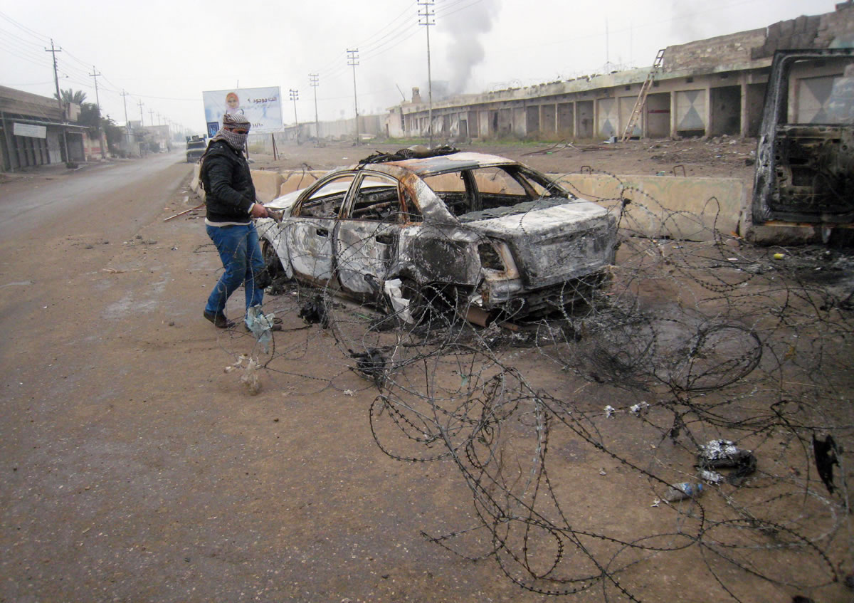 A gunman clears debris Friday after clashes in Fallujah, Iraq.