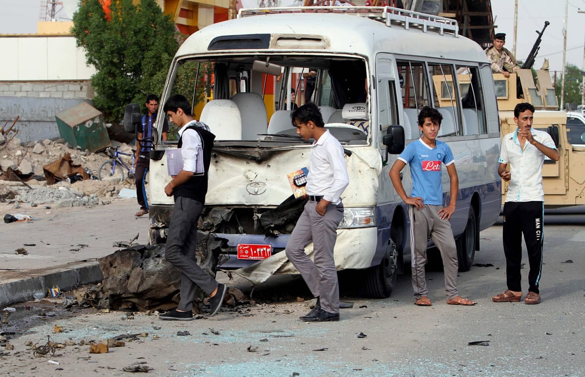 Students inspect their damaged school bus Nov. 10 at the site of a car bomb attack in Basra, 340 miles southeast of Baghdad, Iraq. The number of Iraqis slain &quot;execution-style&quot; surged last month, the U.N.