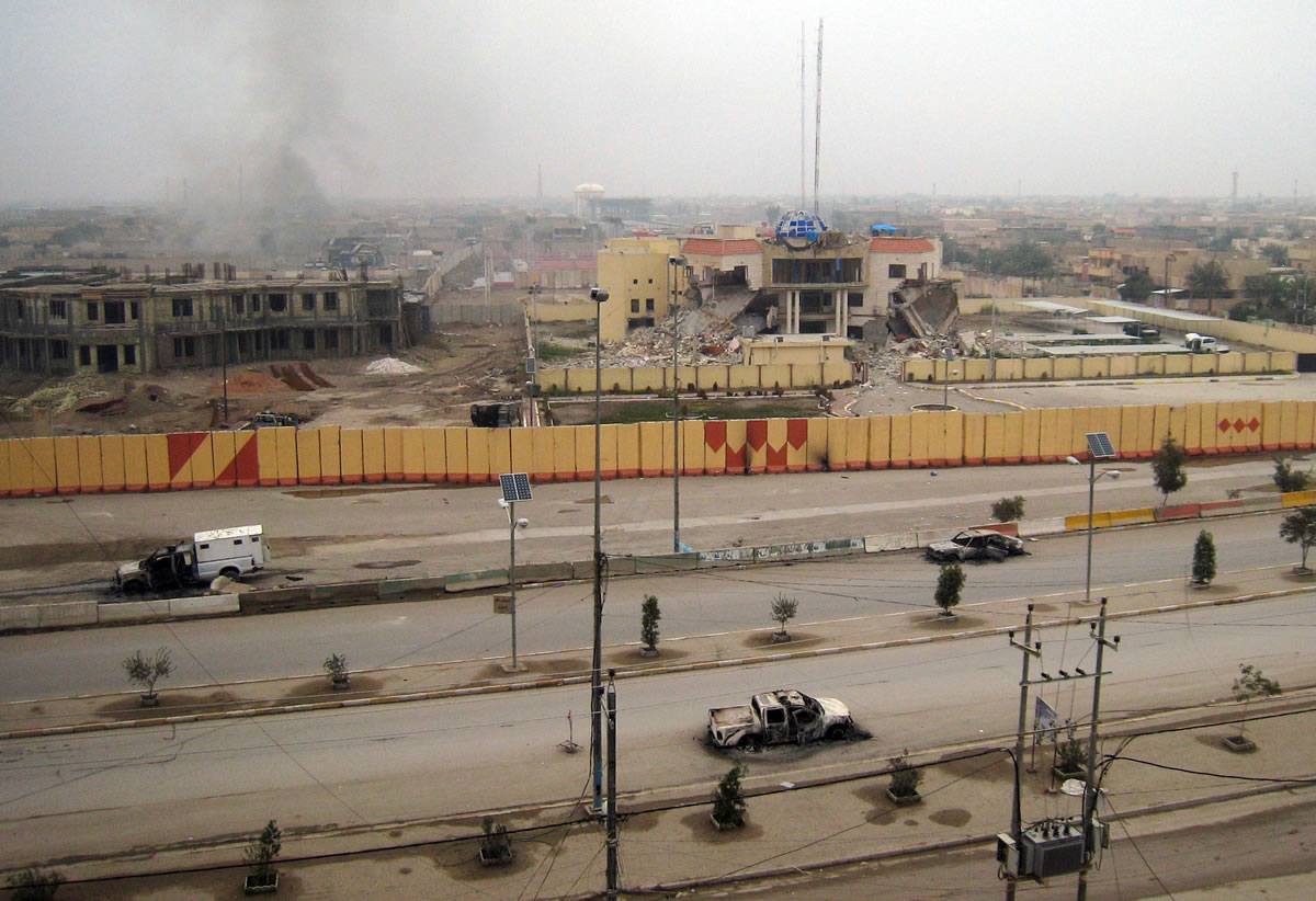 An empty street is littered with burned vehicles, and buildings, including a provincial government building, center, are seen damaged Friday in Fallujah, Iraq, 40 miles west of Baghdad.